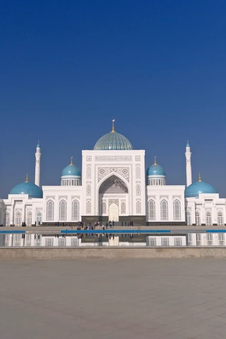 Minor Mosque's white marble and blue domes reflected in its pool